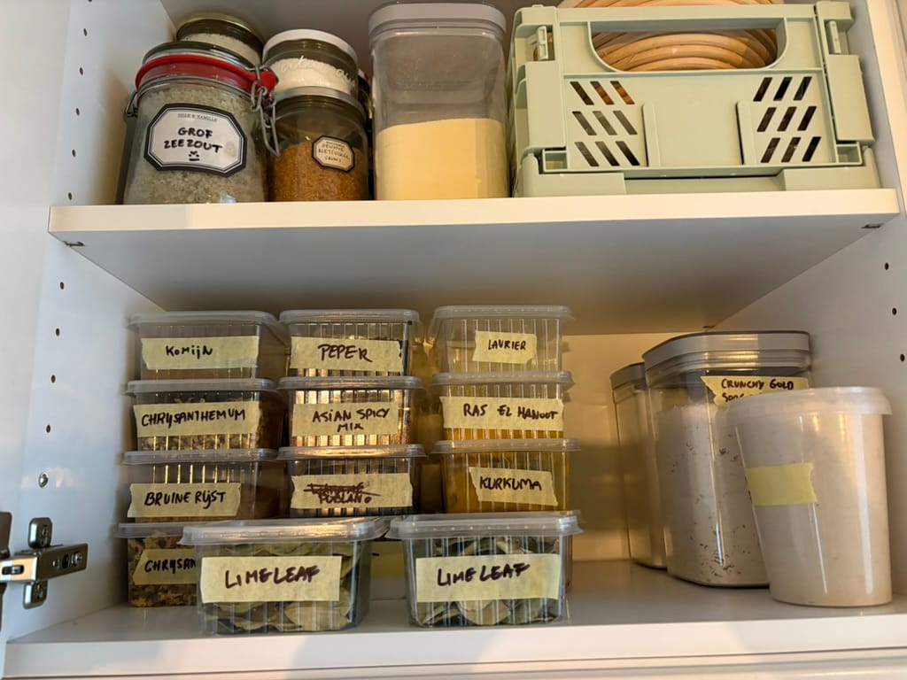 Stacked plastic boxes of spices with masking tape stuck on containing what spice is in the container
