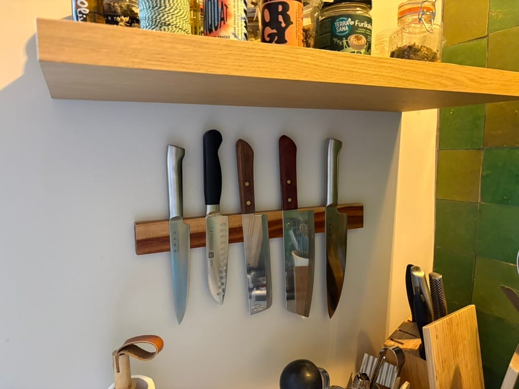 5 different kitchen knives on an acacia wooden magnetic knife strip